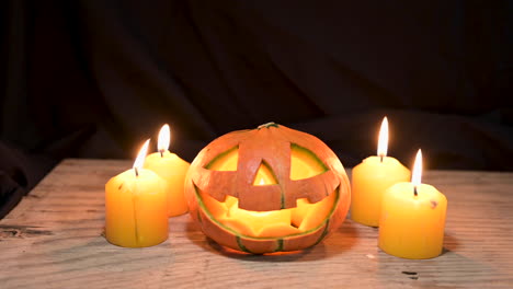 Halloween-Kürbis-Mit-Kerzenlicht-Auf-Holz-Im-Dunklen-Raumhintergrund