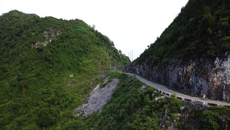 Drone-shot-up-a-mountain-to-reveal-a-motorcyclist-travelling-along-a-road-on-Vietnam's-Ma-Pi-Leng-Pass