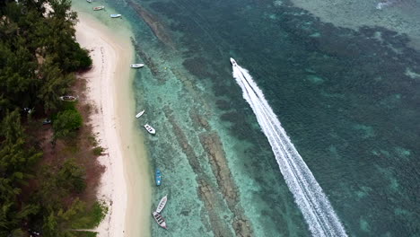 Private-beach-area-overhead-birds-eye-view-looking-down-to-moving-highspeed-boat