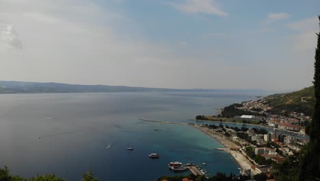 Hazy-sun-over-Adriatic-and-Omis-town,-drone-footage-landing