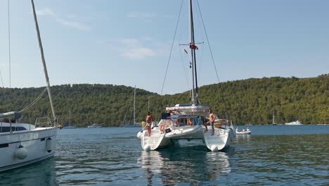 Sailboat-catamaran-docking-with-people-onboard-on-Adriatic-sea,-Mljet-island,-Croatia