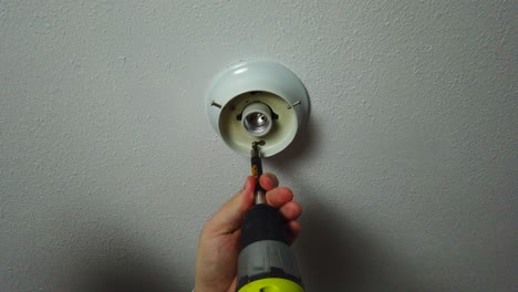 Unscrewing-with-a-drill-an-old-light-and-removing-it-from-the-cieling