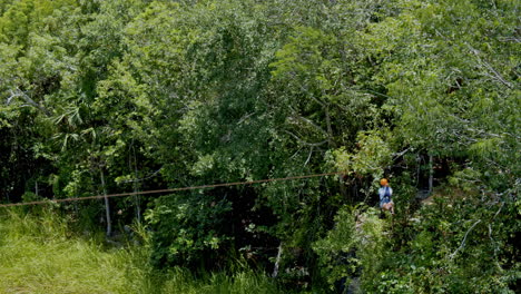 Side-shot-of-girl-zip-lining-over-the-pond-in-the-middle-of-the-forest,-Cancùn,-Mexico