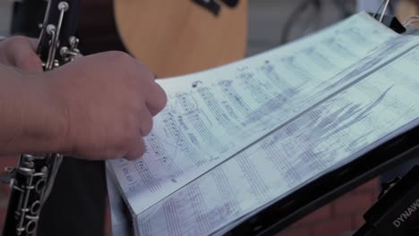 Der-Musiker-Hält-Eine-Klarinette-Und-Blättert-Seiten-Mit-Musiknoten-Um
