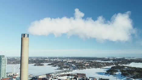 Aerial-shot-of-a-flue-gas-stack-in-Winter,-slowly-pulling-out