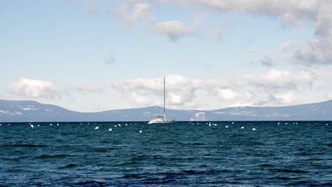 Sailboat-and-buoys-in-Lake-Tahoe-California-on-cloudy-day,-Handheld-stable-shot