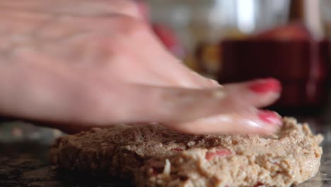 Close-up-of-woman-fingers-stretching-whole-wheat-flour-dough-on-countertop