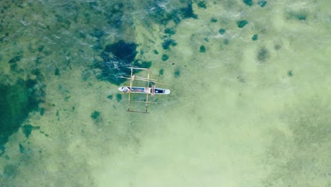 Aerial-top-down-drone-shot-of-a-phishing-boat-on-clear-water-in-Zanzibar,-Tanzania