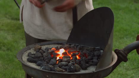 A-revolutionary-war-reinacter-blacksmith-pulls-a-piece-of-metal-out-of-hot-coals