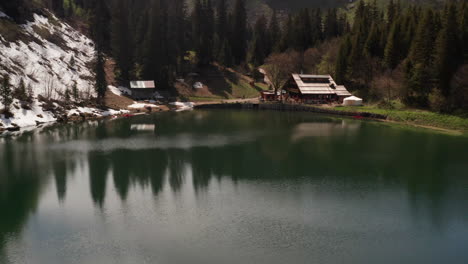 Aerial-of-idyllic-cabin-near-beautiful-lake-in-nature