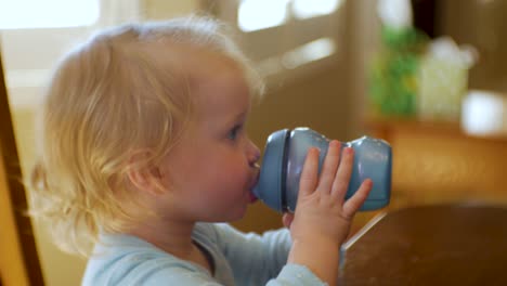 Adorable-female-toddler-drinks-water,-joice-or-milk-from-her-sippy-cup---close-up
