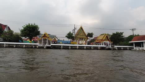 Blick-Von-Einem-Boot-Auf-Den-Thailändischen-Tempel-Und-Den-Kai-Des-Kanals-In-Bangkok,-Thailand