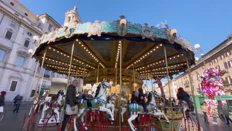 People-Riding-The-Ancient-German-Horse-Carousel-In-Front-Of-Sant'Agnese-In-Agone,-Piazza-Navona-In-Rome,-Italy