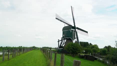4k-Windmill-Oukoopse-Molen-standing-in-typical-Dutch-nature-with-green-lands,-dutch-culture-leadinglines