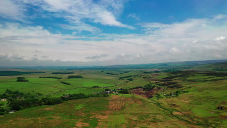 Aerial-shot-looking-over-the-rolling-green-countryside-of-Cumbria,-bright-sunny-day