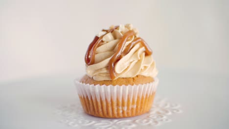 One-peanut-flavor-cupcake-rotating-slowly-on-white-decorated-plate,-front