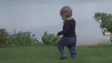 Slow-motion-shot-of-child-walking-towards-water-with-dogs-by-his-side