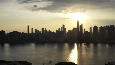 a-slow-dramatic-pan-right-of-a-drone-camera,-aerial-view-of-New-York-City's-east-side,-during-a-golden-sunset-in-the-summer-time