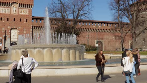 Menschen,-Die-An-Einem-Strahlend-Sonnigen-Tag-Fotos-Machen-Und-Am-Brunnen-Vor-Der-Festung-Des-Sforzesco-Schloss-In-Mailand,-Italien,-Hängen