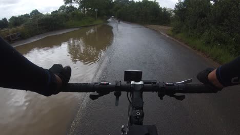 Punto-De-Vista-En-Bicicleta-Alrededor-De-Una-Carretera-Parcialmente-Inundada-Con-Un-Automóvil-Que-Se-Aproxima