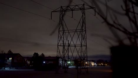 Revealing-shot-of-a-hydro-tower-at-night-in-a-snowy-suburban-area