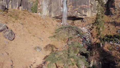 Luftaufnahme-Von-Menschen,-Die-Im-Winter-Unter-Den-Jogini-Wasserfällen-In-Der-Nähe-Von-Manali,-Himachal-Pradesh,-Spielen,-Aufgenommen-Mit-Einer-Drohne,-Die-über-Große-Bäume-Fliegt,-In-4K