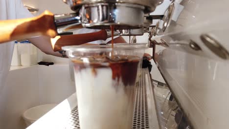 Coffee-machine-dripping-coffee-on-a-glass-of-milk
