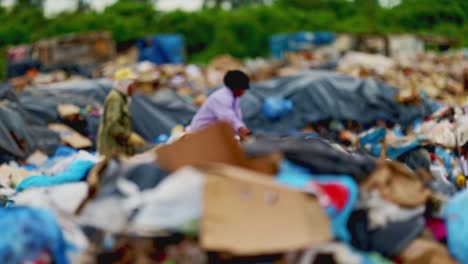 Two-impoverished-people-sift-through-piles-of-garbage-at-a-city-dump
