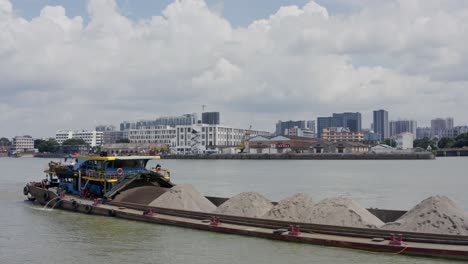 Chinese-river-barge-vessel-full-loaded-with-sand-bulk-cargo-underway-on-Zhujiang-River,-on-a-cloudy-day