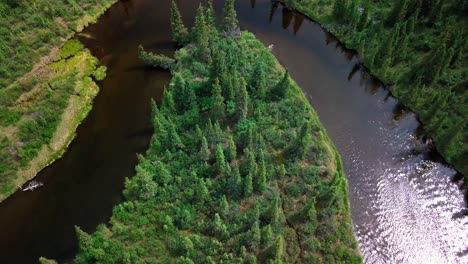 Birdseye-flight-above-Yukon-shiny-reflective-and-rippling-Jarvis-Creek-bend-river-by-evergreen-trees-in-forest-on-bright-sunny-day,-Canada,-overhead-aerial-pull-back