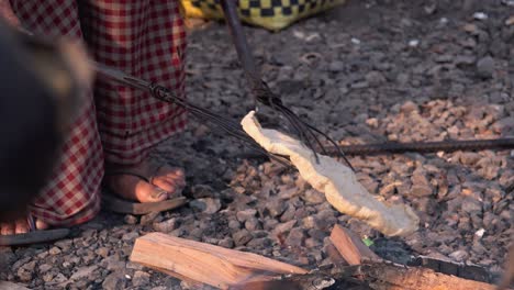 Close-Shot-of-Flat-Bread-Being-Cooked-Over-Open-Flames-With-Two-Long-Sticks-With-Prongs-at-The-End-of-them-to-Flip-the-Bread