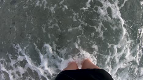legs-of-a-girl-standing-on-a-pebble-beach-washed-by-waves-then-leaving-the-spot-at-the-end-of-the-video