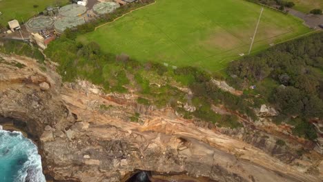 Epische-Drohnenaufnahme-Von-Meereswellen,-Die-Gegen-Klippen-Und-Felsen-Schlagen,-In-Der-Nähe-Eines-Parks,-Sydney,-Australien