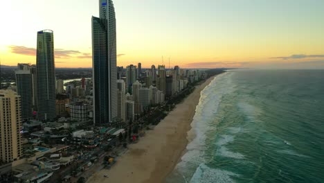 Surfers-Paradise-at-Sunset,-High-rise-buildings,-crashing-waves-on-golden-beaches