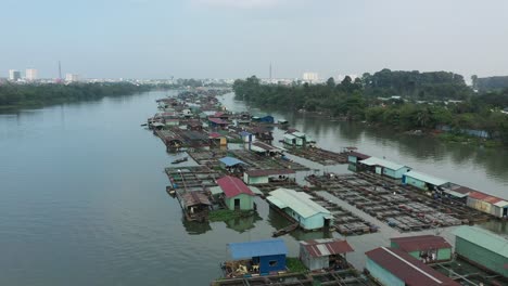 slow-tracking-drone-shot-over-floating-fish-farming-community-in-Bien-Hoa-on-the-Dong-Nai-river,-Vietnam-on-a-sunny-day