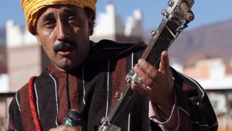 Berber-musician-looking-at-camera-while-playing-rabab-and-singing-in-Taffraoute,-Morocco