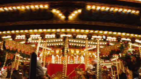 Close-up-view-of-bright-lights,-Christmas-decorations-and-riders-enjoying-a-spin-on-a-carousel-while-visiting-a-fair