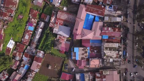 Top-down-drone-video-of-the-garden,-road,-cars,-and-motorcycle,-houses-with-worn-out-roof-in-the-small-town-in-Asia,-North-Sumatera,-Indonesia