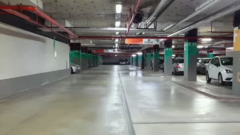 Car-Driving-On-Underground-Parking-Area-With-Cars-Parked-In-Burgas,-Bulgaria---POV,-wide-shot