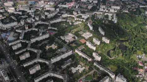 Aerial-View-of-Geometrically-Shaped-Buildings-in-a-City-Surrounded-by-Trees-Pan-Down