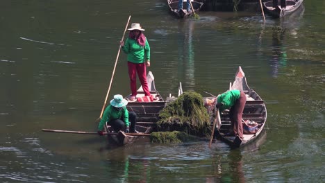 Medium-Shot-of-Asian-Ladies-in-Boats-Cleaning-the-Moat-Around-Angkor-Wat-in-Cambodia