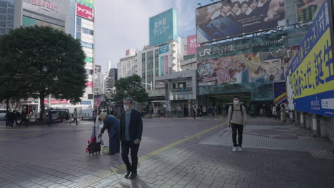 Gente-Caminando-Y-Pasando-Por-Un-Hombre-Vestido-Como-Donald-Trump-Frente-A-La-Estación-De-Shibuya-Cerca-Del-Cruce-De-Shibuya-En-Tokio,-Japón-Durante-Covid-19