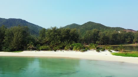 Peaceful-lagoon-with-calm-clear-water-washing-white-sand-of-exotic-beach-on-shore-with-green-trees-and-palms-garden-resort-in-Koh-Phangan,-Thailand