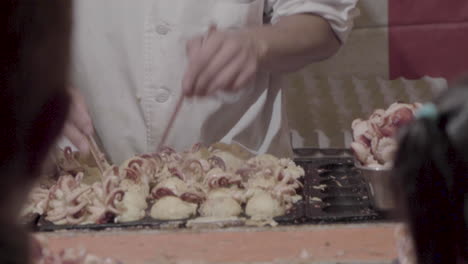 Professional-male-cook-is-preparing-japanese-food-called-Takoyaki-with-chopsticks-pretty-fast