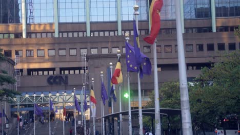 European-flags-and-Belgian-flags-waving-in-the-wind-in-the-city-of-Brussels,-Belgium,-at-the-Brussels-Northern-train-station-on-a-sunny-summer-morning