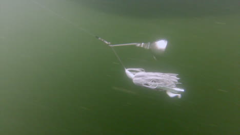 Dragging-The-White-Tailed-Spinnerbait-On-Green-Seawater-Surface---Closeup-Shot-Slow-Motion
