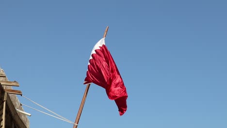 A-view-of-Qatar-National-Flag-waving-at-Souq-Waqif-in-Doha,-Qatar