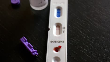 Close-up-of-rapid-antigen-Covid-test-kit,-lancet-and-buffering-solution,-showing-a-negative-result