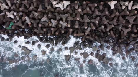 Aerial-view-of-sea-wave-crashing-tetra-concrete-block-or-wave-breaker-stone-at-Glagah-beach,-Indonesia