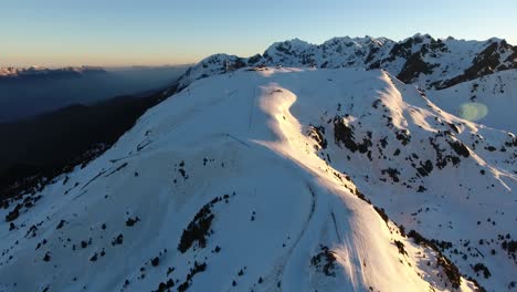 Downhill-ski-track-at-the-Chamrousse-French-Alps-during-sunrise,-Aerial-dolly-out-shot